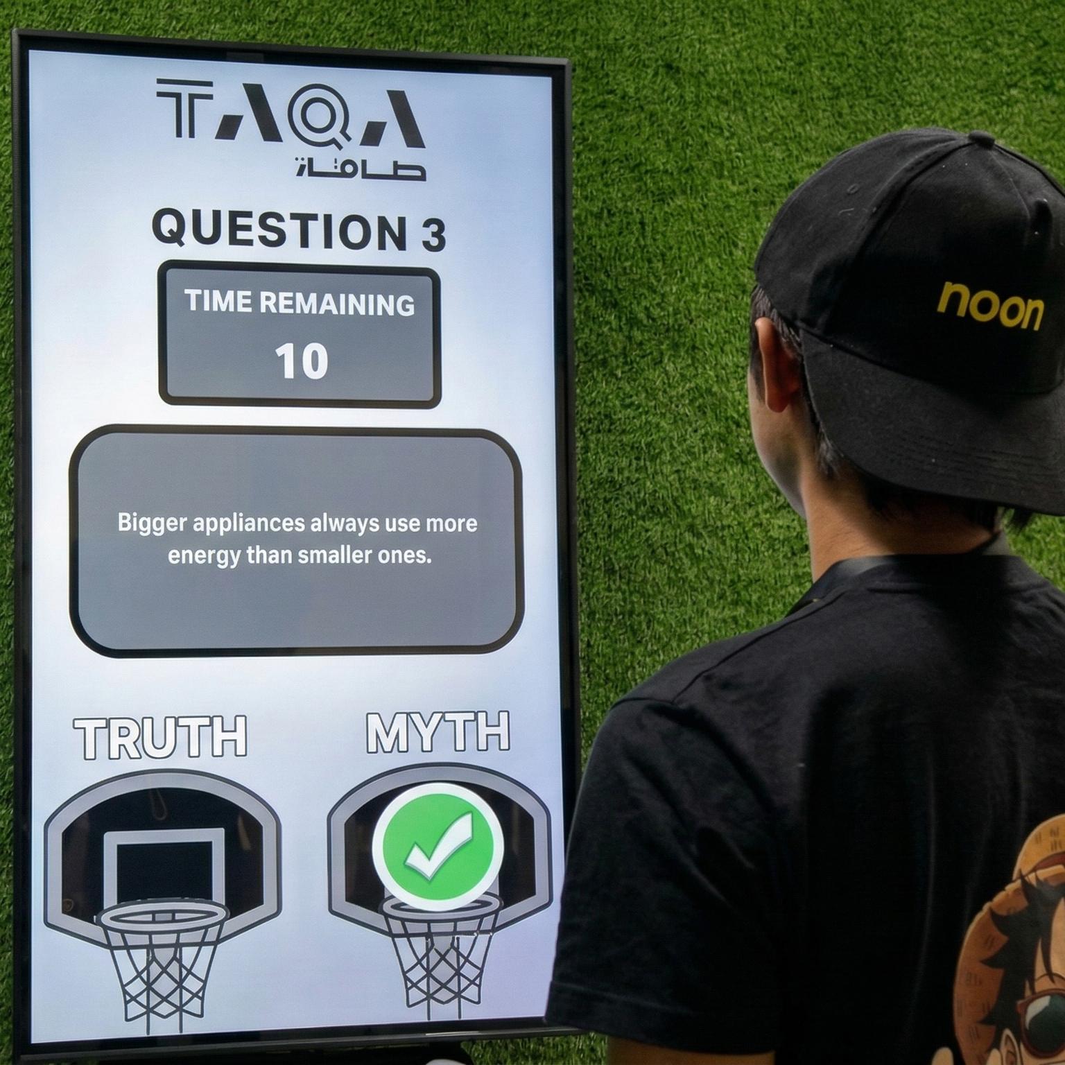 A guest throwing a softball at a large digital Truth or Myth display screen to lock in an answer at a high-energy corporate exhibition booth activation
